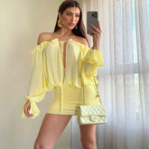 Woman in a yellow outfit taking a mirror selfie with a matching handbag.